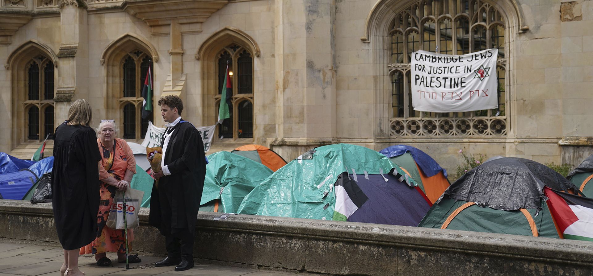 Estudiantes graduados se encuentran cerca de un campamento de protesta por el conflicto de Gaza en los terrenos de la Universidad de Cambridge, Inglaterra, el viernes 17 de mayo de 2024. (Joe Giddens/PA vía AP) Estudiantes graduados se encuentran cerca de un campamento de protesta por el conflicto de Gaza en los terrenos de la Universidad de Cambridge, Inglaterra, el viernes 17 de mayo de 2024. (Joe Giddens/PA vía AP)