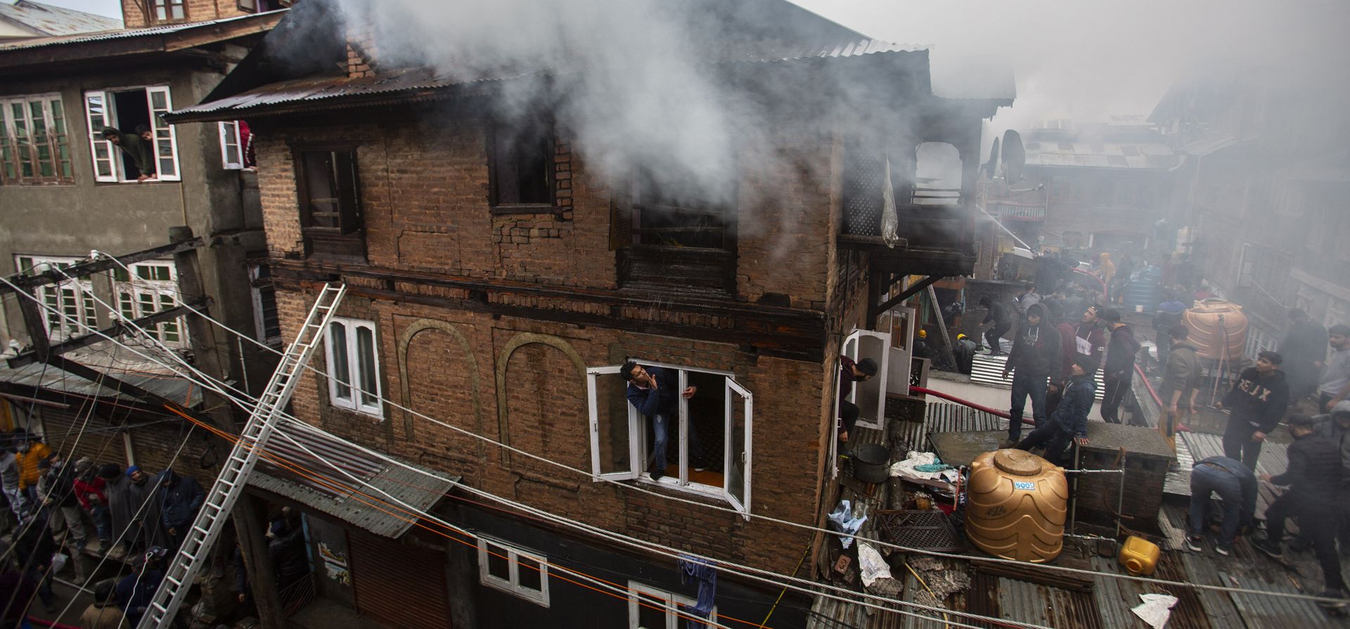 Bomberos y civiles trabajan para extinguir un incendio en Srinagar, Cachemira, el jueves 20 de enero de 2022. Tres civiles resultaron heridos y muchas casas residenciales resultaron dañadas en el incendio.