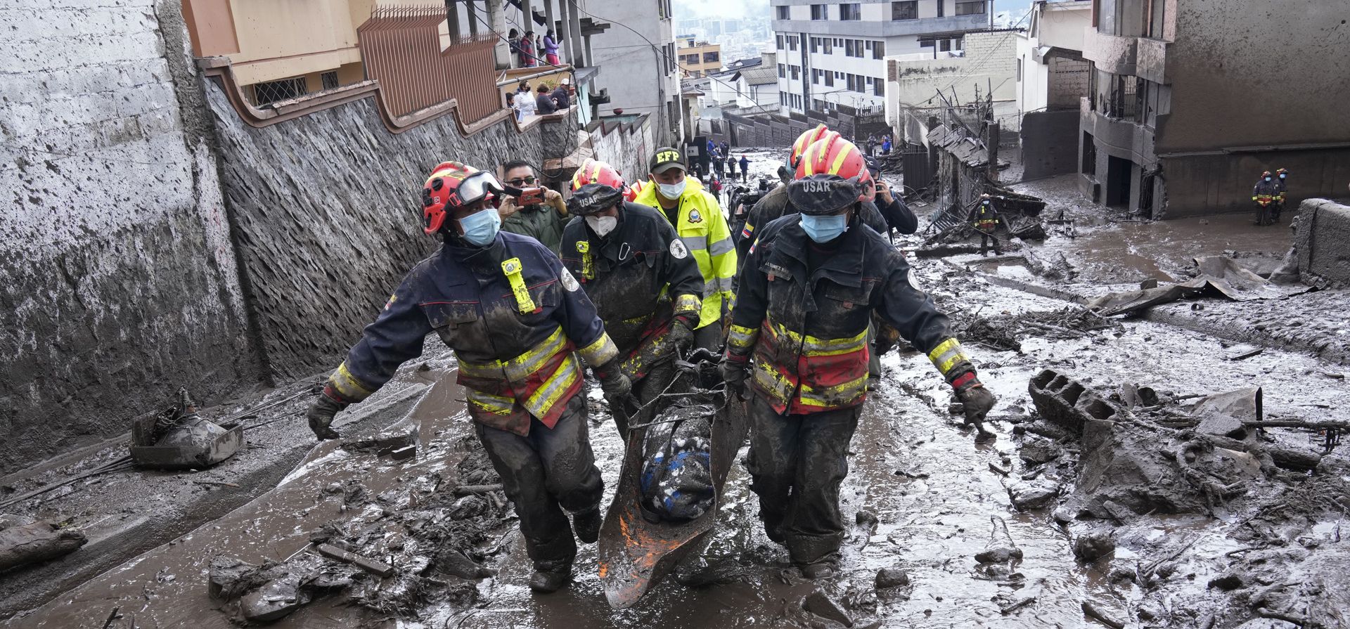 Rescatistas se llevan el cuerpo de una víctima de una inundación repentina provocada por la lluvia que llenó los arroyos cercanos y reventó su mecanismo de contención en el barrio La Comuna de Quito, Ecuador, el martes 1 de febrero de 2022.