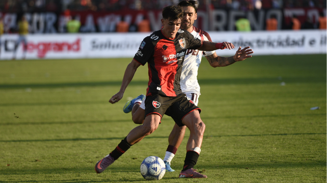 Martín Ortega traslada la pelota perseguido por Salvio durante el partido entre Newells y Lanús.