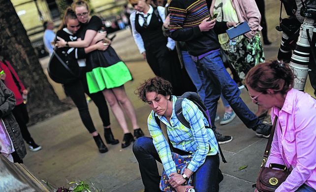 Dolor. Jóvenes depositan flores en un memorial a las víctimas del ataque explosivo al final de un recital.