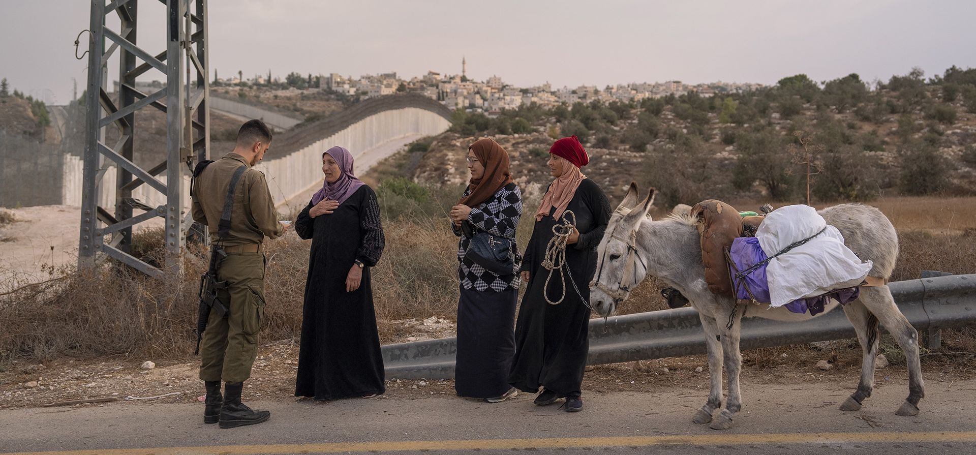 Un soldado israelí verifica el permiso de entrada de los agricultores palestinos para permitirles cruzar a su tierra para cosechar aceitunas, en la aldea de Beit Awwa, en Cisjordania, cerca de Hebrón, el miércoles 26 de octubre de 2022.