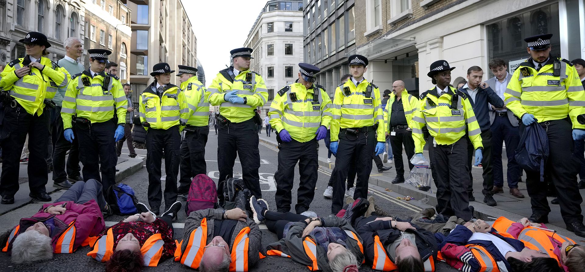 Activistas esposados del grupo Just Stop Oil yacen en la calle mientras son arrestados después de bloquear el paso vehicular en Londres, el jueves 27 de octubre de 2022, exigiendo que se detengan los proyectos futuros de gas y petróleo.