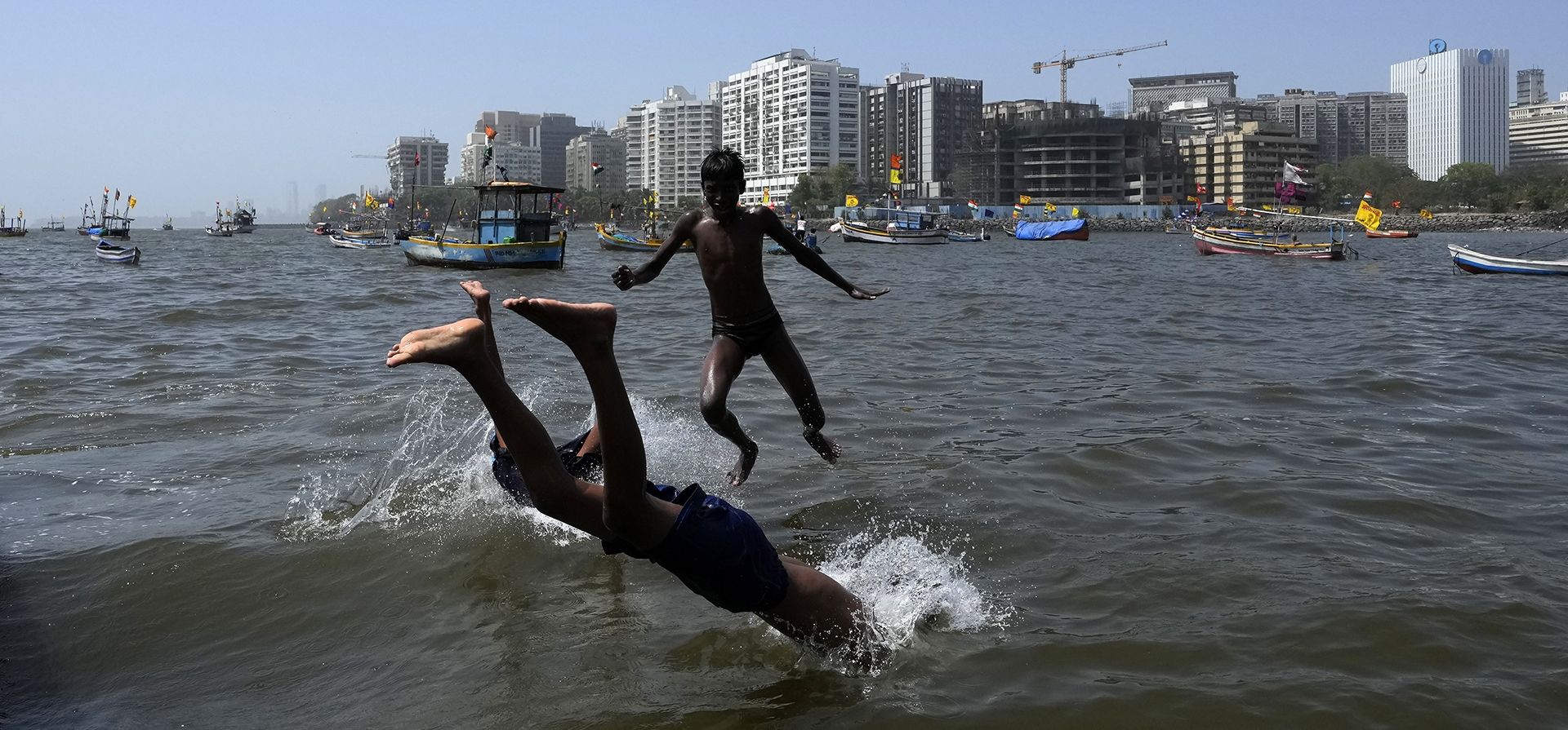 Niños saltan a las aguas del Mar Arábigo en Mumbai, India, el viernes 1 de abril de 2022.