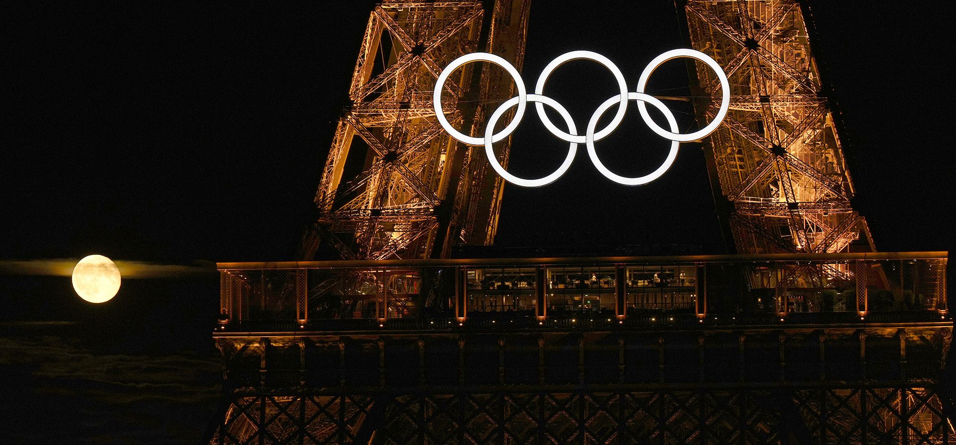 La luna llena sale detrás de los anillos olímpicos que cuelgan de la Torre Eiffel el lunes 22 de julio de 2024 en París, Francia. La ceremonia inaugural de los Juegos Olímpicos es el viernes. (Foto AP/David J. Phillip) La luna llena sale detrás de los anillos olímpicos que cuelgan de la Torre Eiffel el lunes 22 de julio de 2024 en París, Francia. La ceremonia inaugural de los Juegos Olímpicos es el viernes. (Foto AP/David J. Phillip)
