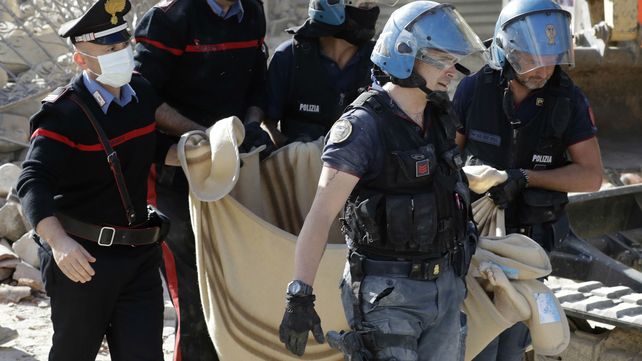 Efectivos policiales y socorristas trasladan el cadáver de una de las víctimas en&nbsp;Amatrice