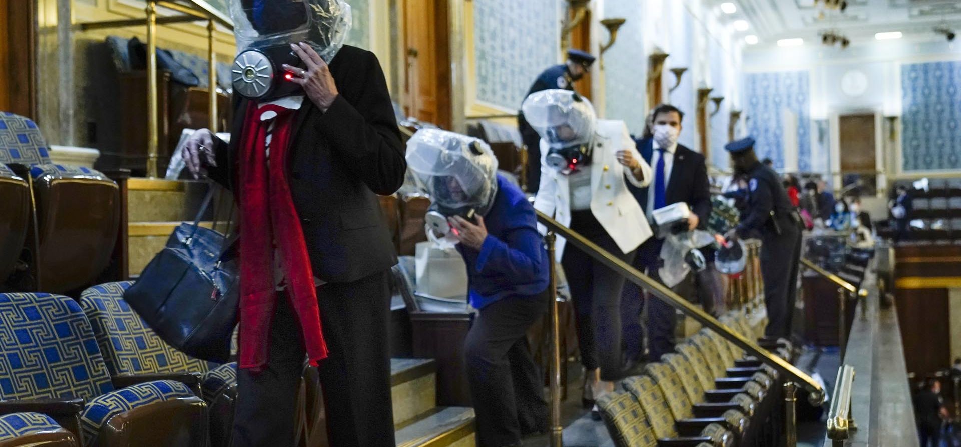 Miembros del Congreso usan máscaras de gas de emergencia cuando son evacuados de la galería de la Cámara mientras los manifestantes intentan irrumpir en la Cámara del Capitolio de los Estados Unidos el 6 de enero de 2021 en Washington. 