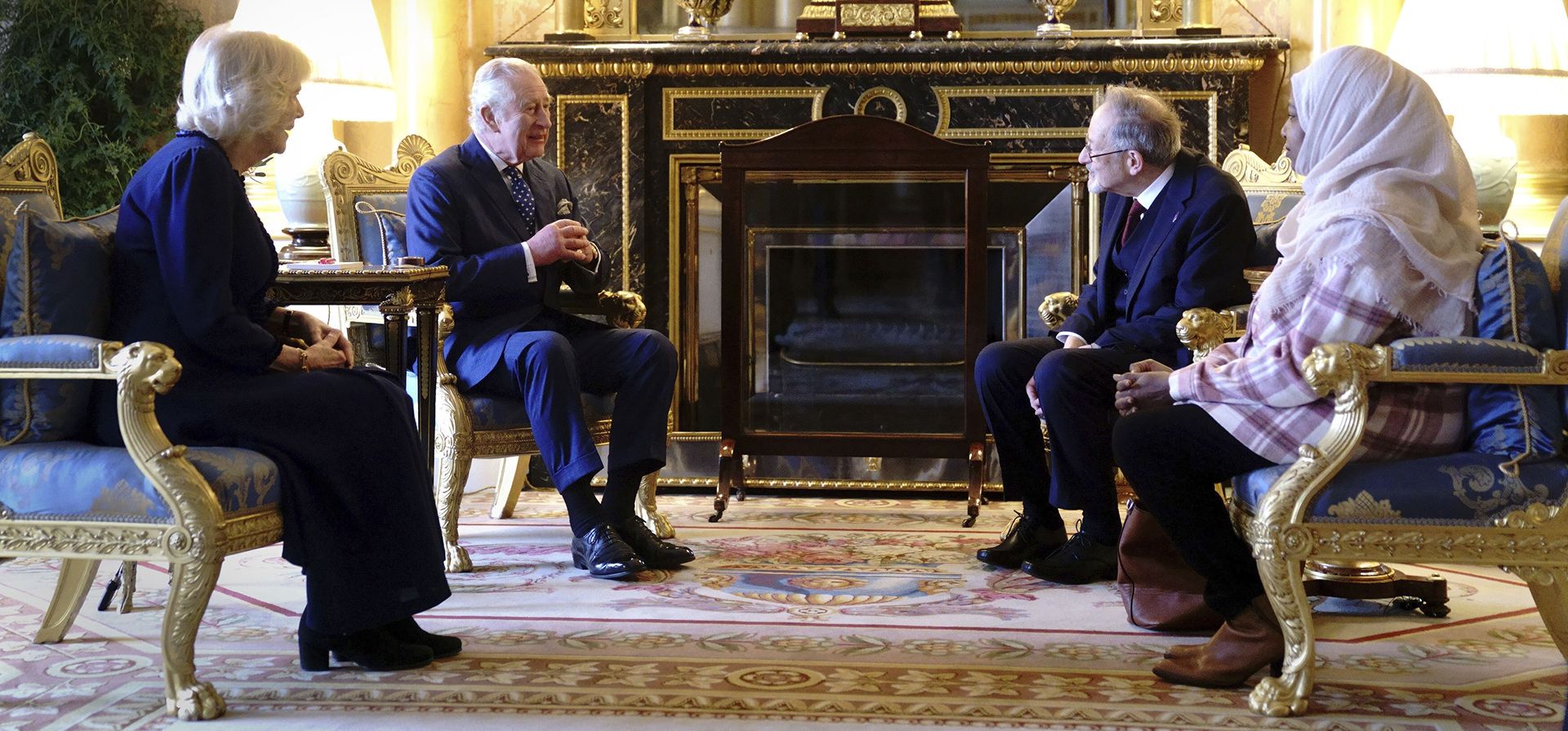 El rey Carlos III de Gran Bretaña y Camila, la reina consorte hablan con Amouna Adam, a la derecha, sobreviviente del genocidio de Darfur, y el sobreviviente del Holocausto, el Dr. Martin Stern, segundo a la derecha, después de encender velas en el Palacio de Buckingham, Londres, el viernes 27 de enero de 2023, para conmemorar el Día de la Memoria del Holocausto. (Victoria Jones/Foto de la piscina vía AP)