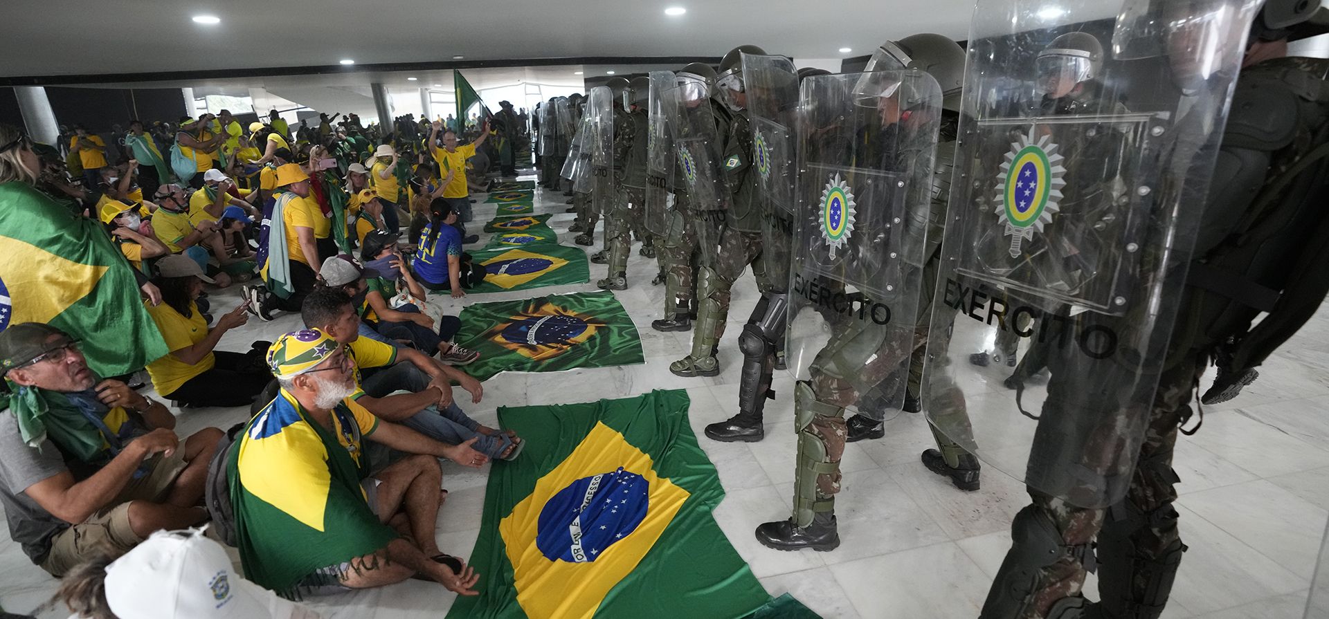 Manifestantes, simpatizantes del expresidente de Brasil, Jair Bolsonaro, se sientan frente a la policía después de ingresar al Palacio de Planalto después de asaltarlo, en Brasilia, Brasil, el domingo 8 de enero de 2023. (Foto AP/Eraldo Peres)