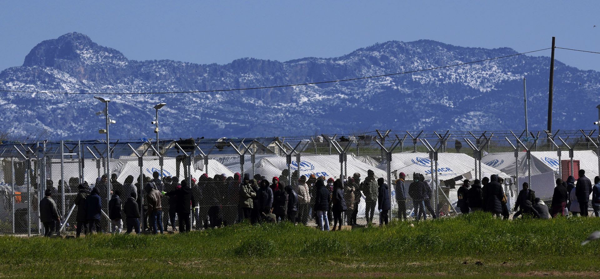 Migrantes esperan detrás de una valla durante la visita del presidente de Chipre, Nicos Anastasiades, al centro de recepción de migrantes pournara en Kokkinotrimithia, a las afueras de la capital, Nicosia, Chipre, el lunes 14 de marzo de 2022. Anastasiades dijo después de concluir su breve visita al hacinado campamento de recepción de migrantes.