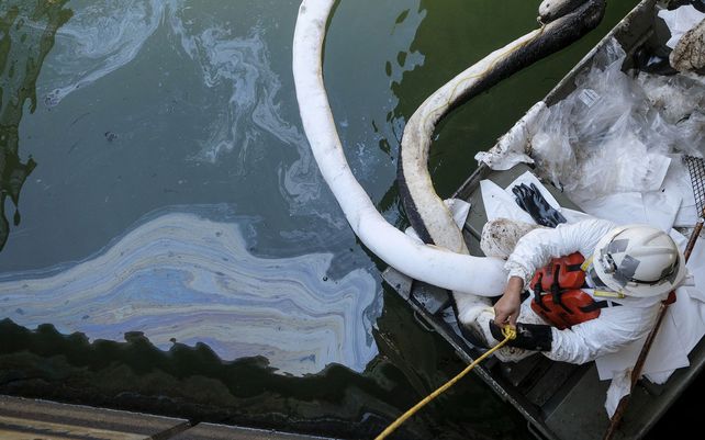 Trabajadores limpian aceite en una entrada que conduce a los humedales Talbert Marsh después de un derrame de petróleo en Huntington Beach, California. Un gran derrame de petróleo frente a la costa del sur de California contaminó playas y mató a la vida silvestre.