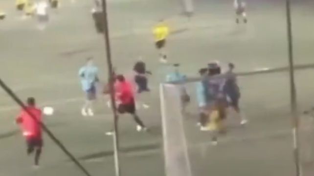 El árbitro (de rojo) golpea con un derechazo a un hincha que ingresó al campo de juego.
