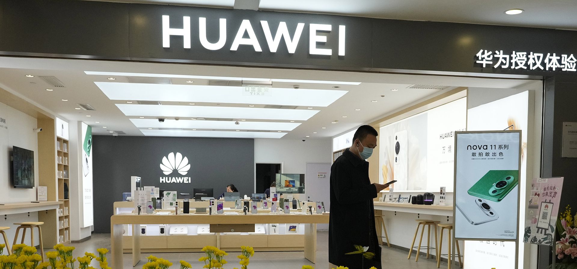 Un hombre pasa junto a un lecho de flores de plástico frente a la tienda de la franquicia Huawei en Beijing el viernes 28 de abril de 2023. El gigante tecnológico chino Huawei informó el viernes que sus ingresos aumentaron un 0,8% respecto al año anterior en los primeros tres meses de 2023 y la compañía fue rentable. (Foto AP/Ng Han Guan)