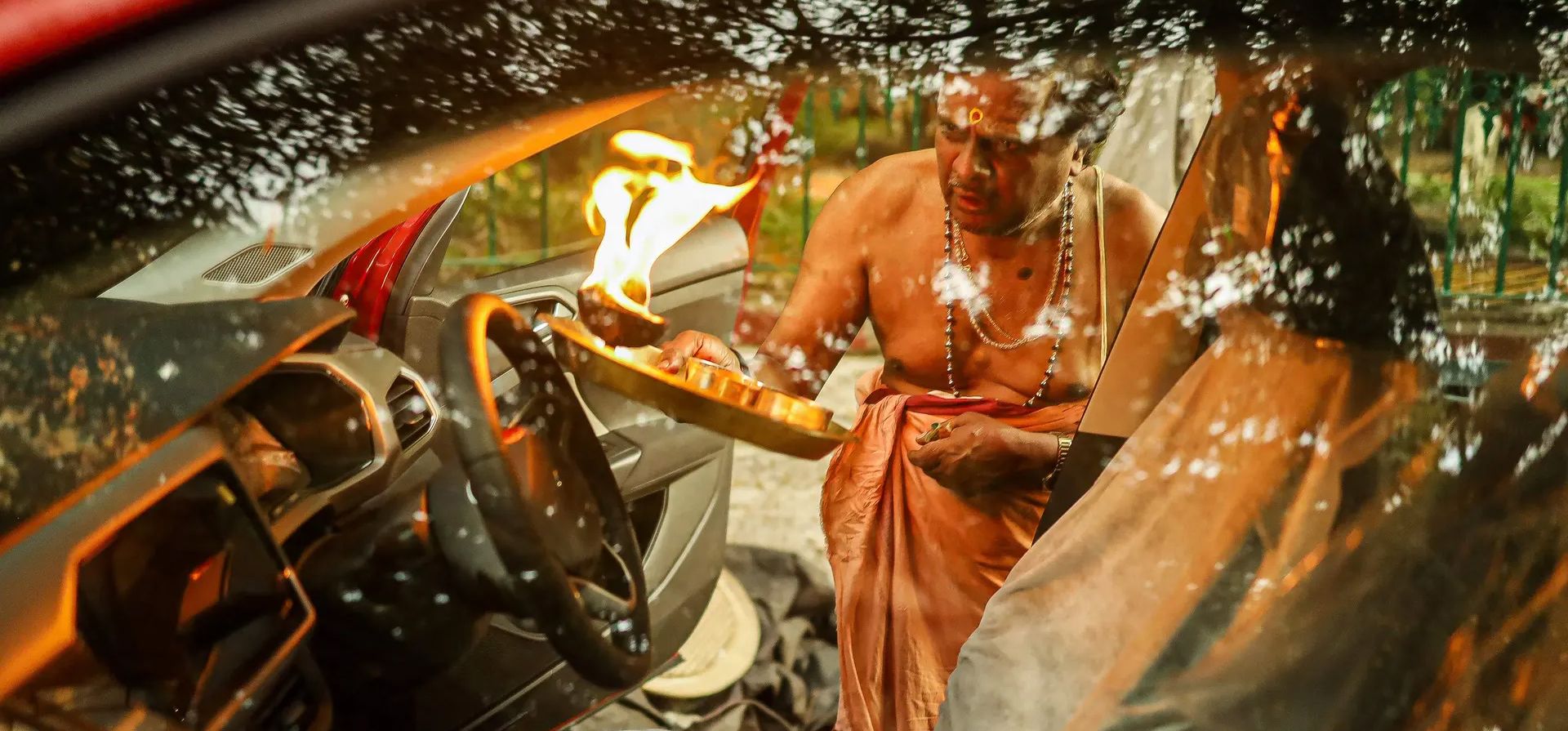 Un sacerdote realiza un ritual en un automóvil recién comprado para buscar bendiciones de las deidades por seguridad fuera de un templo, Bangalore, India. Fotografía: Sebastien Berger/AFP/Getty Images