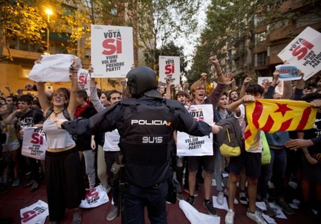 Tensión. Un agente de la Guardia Civil intenta detener el avance de manifestantes que protestaban frente a una de las sedes de gobierno requisadas.