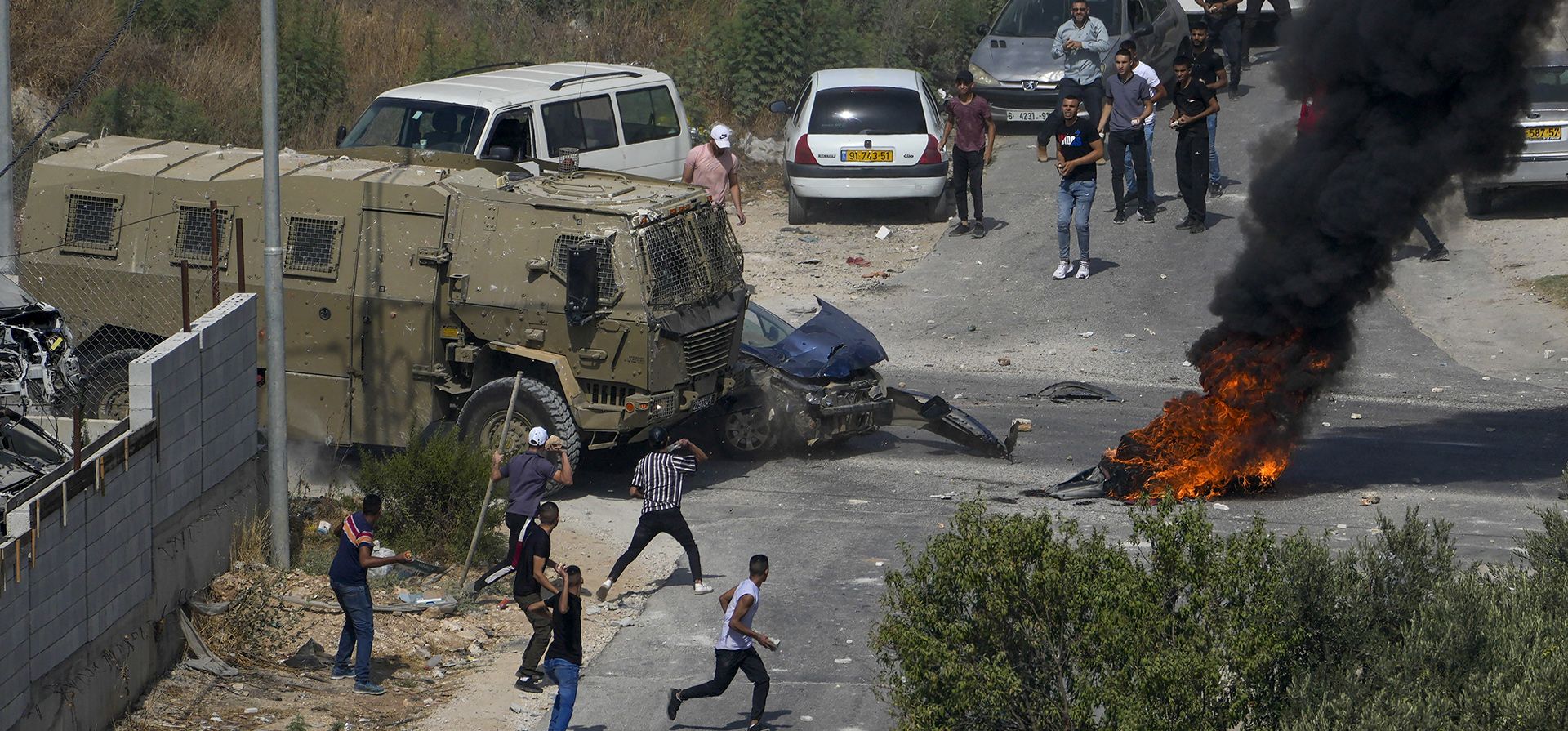 Palestinos arrojan piedras a vehículos militares israelíes durante una operación militar israelí en la aldea de Rujib, en Cisjordania, el martes 30 de agosto de 2022. El ejército dijo que arrestó a 12 palestinos durante redadas en Cisjordania el martes, incluidos dos hombres sospechosos de llevar a cabo un tiroteo la semana pasada.