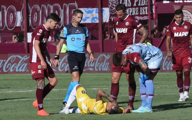 Candia ya sufrió el esguince de rodilla y es auxiliado por el árbitro y varios jugadores de Lanús.