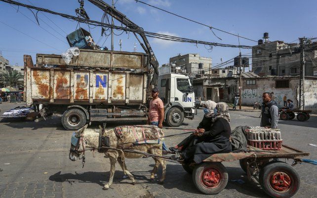Mujeres palestinas montan un carro de burro frente a un camión de basura de la Agencia de Obras Públicas y Socorro de las Naciones Unidas (UNRWA) en el campo de refugiados de Rafah. El nuevo gobierno de Joe Biden, quiere reintroducir el apoyo a los palestinos detenido por el ex presidente Donald Trump.