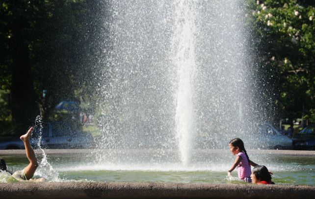 Los chicos se zambullen en la fuente de una plaza de la ciudad para refrescarse.