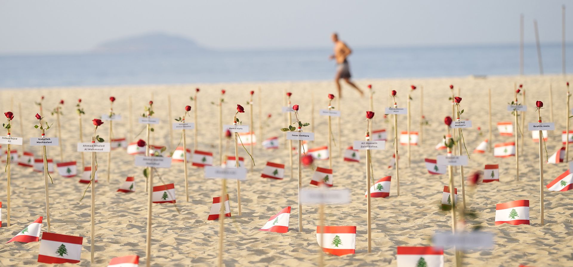 Un hombre pasa junto a las banderas libanesas colocadas en honor a los que murieron en la explosión del puerto de Beirut de 2020 en el tercer aniversario de la explosión, en la playa de Copacabana en Río de Janeiro, Brasil, el viernes 4 de agosto de 2023. (Foto AP/Silvia Izquierdo Un hombre pasa junto a las banderas libanesas colocadas en honor a los que murieron en la explosión del puerto de Beirut de 2020 en el tercer aniversario de la explosión, en la playa de Copacabana en Río de Janeiro, Brasil, el viernes 4 de agosto de 2023. (Foto AP/Silvia Izquierdo