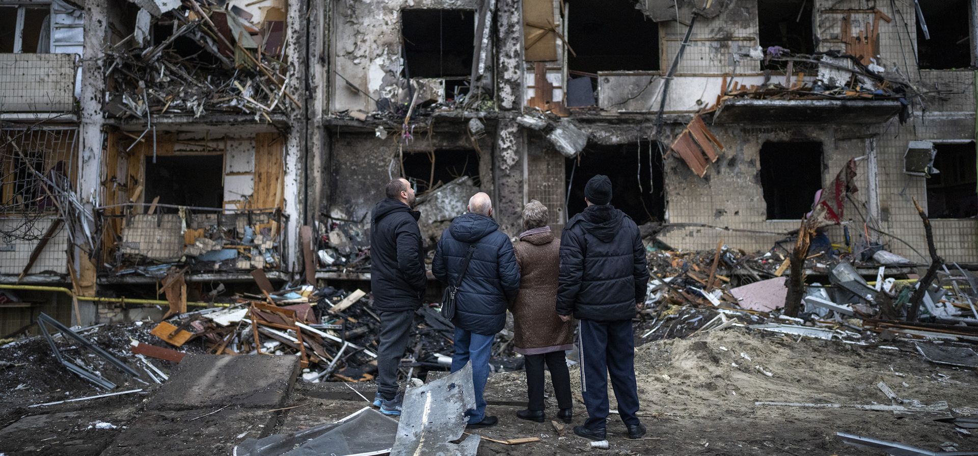 La gente mira los daños del edificio donde redidía después de un ataque con cohetes en la ciudad de Kiev, Ucrania, el viernes 25 de febrero de 2022.