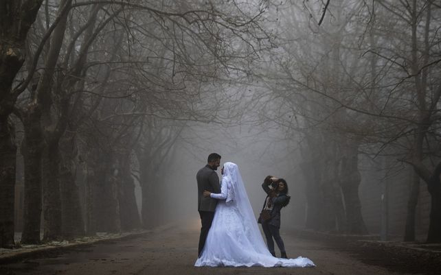 Una pareja de novios posan para una sesión de fotos de boda mientras una densa niebla envuelve la aldea de Sawfar