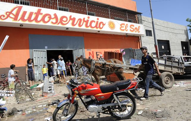 Triste Postal. Un grupo de vecinos ingresa por una de las puertas violentadas de un supermercado de la zona sur de la ciudad.