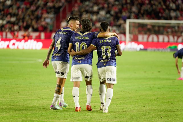 Damián Martínez, Malcorra y Campaz se abrazan tras el gol convertido por el colombiano.