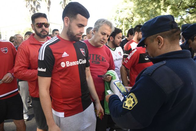 Verificación. El efectivo de la policía escanea con su celular el documento del hincha para saber si le permite entrar al estadio.