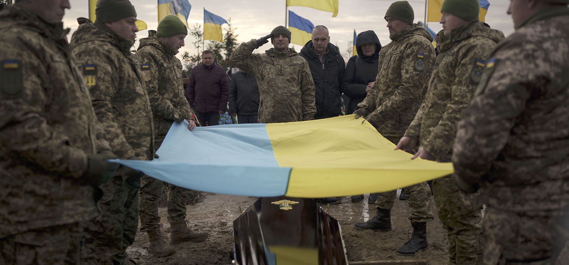 Soldados ucranianos sostienen su bandera nacional sobre el ataúd del camarada Dmytro Kyrychenko, durante su funeral en Bucha, en las afueras de Kyiv, Ucrania, el viernes 23 de diciembre de 2022. El soldado de 33 años murió durante una misión de combate en la región de Donetsk. . (Foto AP/Felipe Dana)