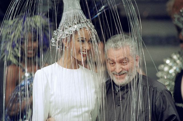 Paco Rabanne posa con una modelo con un vestido blanco con un tocado metálico después de presentar su colección de alta costura otoño-invierno 1992/93 en París