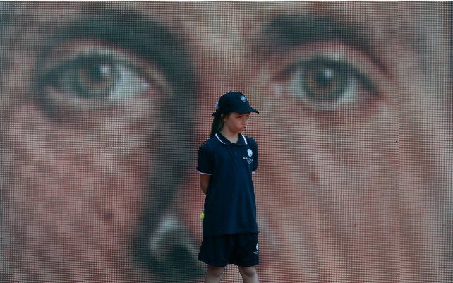 Una chica alcanza pelotas se para frente a una pantalla led que muestra a Novak Djokovic de Serbia antes de su partido de tenis del torneo de tenis abierto de Belgrado contra Mats Moraing de Alemania, en Belgrado, Serbia.