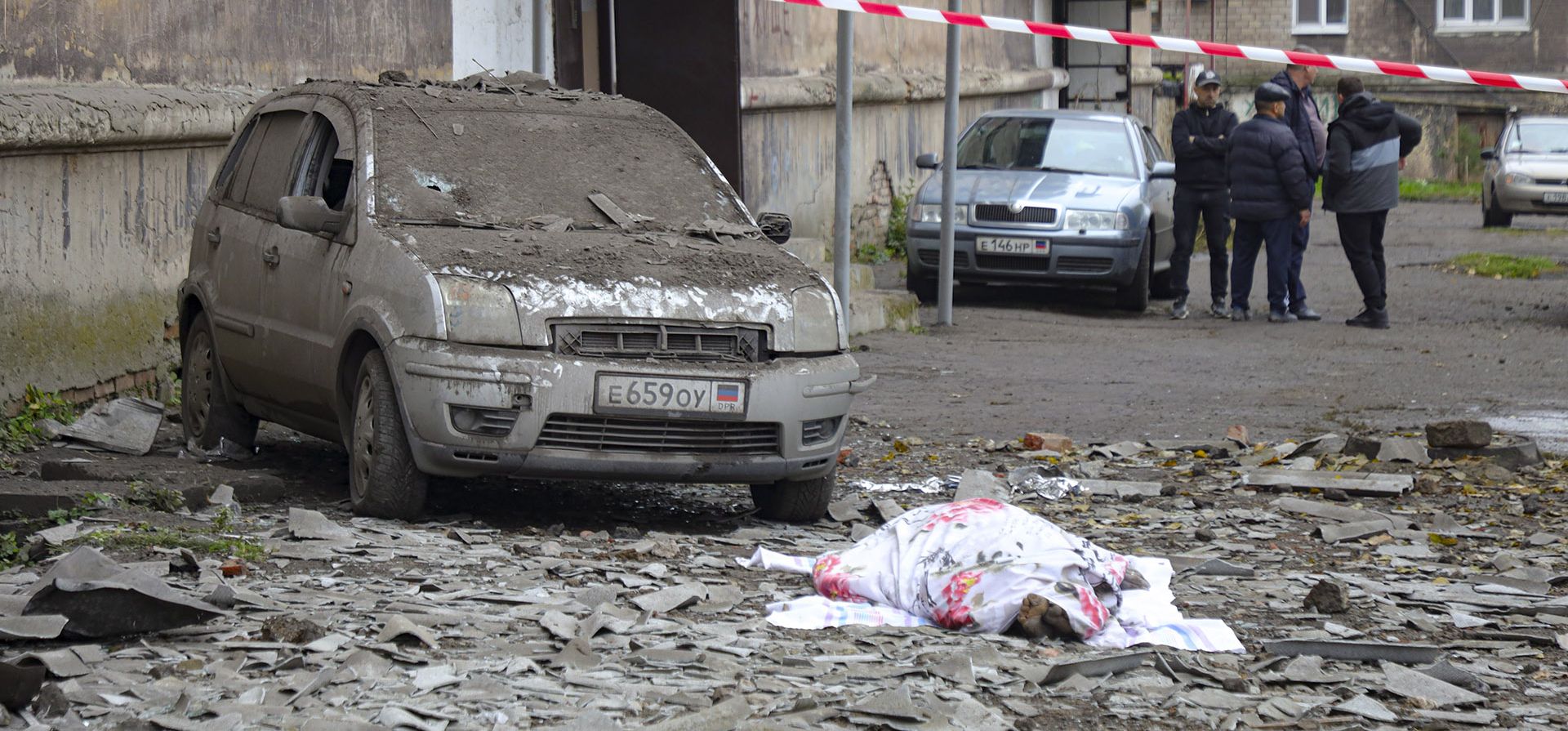 Un cuerpo sin vida cubierto yace junto a un automóvil dañado después del bombardeo de las fuerzas ucranianas en Makiivka, República Popular de Donetsk, este de Ucrania, el viernes 4 de noviembre de 2022.