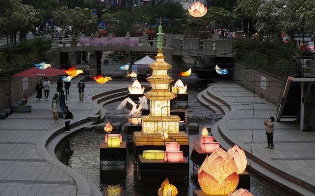 Visitantes caminan cerca de las linternas que se exhiben para la próxima celebración del cumpleaños de Buda el 19 de mayo en la corriente pública en Seúl