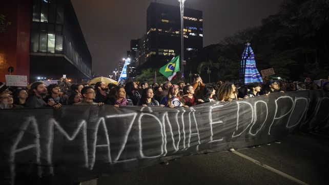 Manifestantes marchan sobre una avenida de San Pablo con una leyenda en portugués: La Amazonia pertenece a la gente.