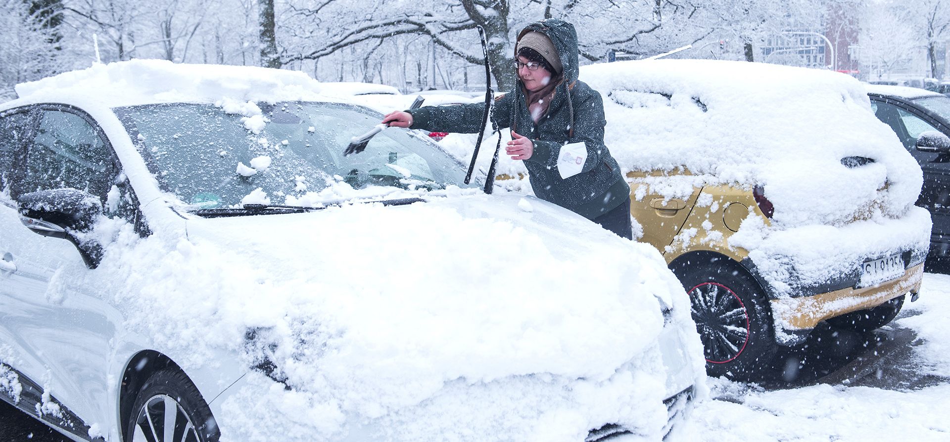 Una mujer limpia su auto durante una nevada en Hamburgo, Alemania, el jueves 31 de marzo de 2022.