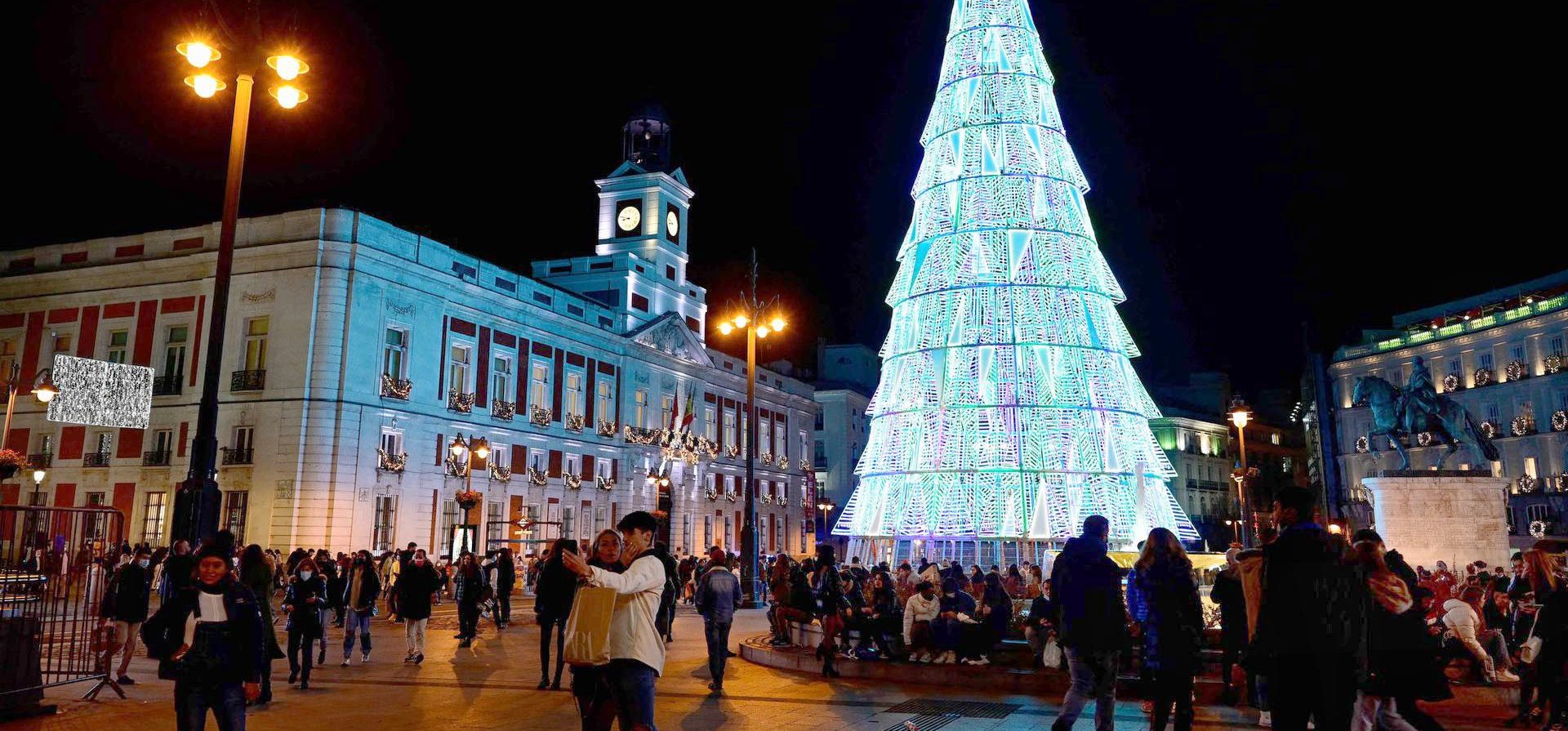 La gente camina frente a las luces navideñas en las calles de Madrid. Foto: AFP