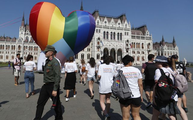 Activistas pasan junto a un gran corazón de colores del arco iris erigido frente al edificio del parlamento del país en Budapest