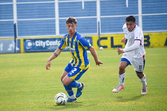 El zaguero central Marco Vicente intenta una salida clara ante el asedio del jugador de San Lorenzo.