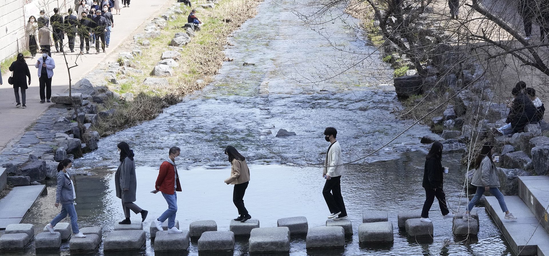 Turistas cruzan el arroyo Cheonggye en el centro de Seúl, Corea del Sur, el martes 29 de marzo de 2022. Corea del Sur reporta 490.881 nuevos casos y supera los 10 millones de contagios por COVID-19.