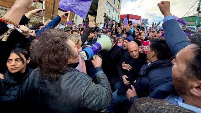 El presidente Javier Milei habla con un megáfono frente a un grupo de seguidores. No pudo recorrer Ushuaia por las protestas en su contra.