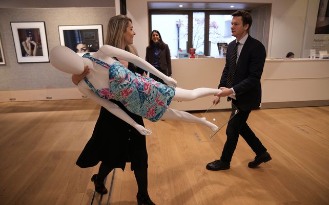 Una mujer lleva un maniquí con un vestido de cuello halter de la marca Dixiefried by Pinnup Couture, usado por la cantante británica Amy Winehouse durante una actuación en enero de 2011 en Río de Janeiro, Brasil, en la casa de subastas Bonhams en Londres.