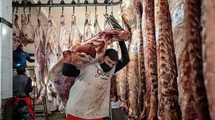 Una postal que se busca dejar atrás: trabajadores que cargan pesadas medias reses