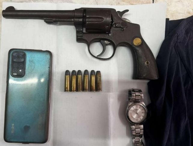 El arma plantada a la víctima y uno de los celulares sustraídos por los policías de la Brigada Motorizada en el operativo ilegal.