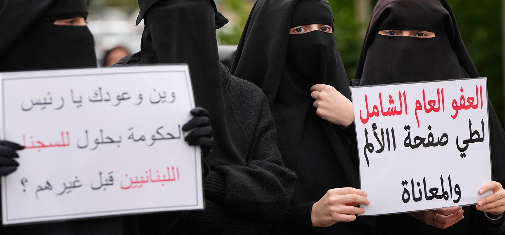 Mujeres sostienen carteles con la leyenda en árabe 