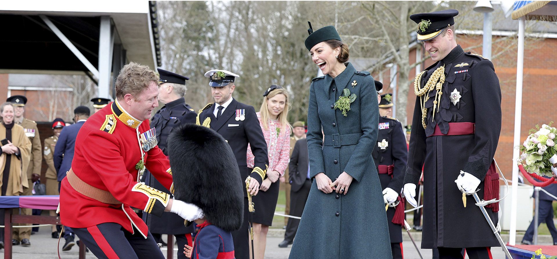 Kate, la duquesa de Cambridge y el príncipe William de Gran Bretaña se ríen mientras el teniente coronel Rob Money pone un sombrero de piel de oso en la cabeza de su hija Gaia Money, de 20 meses, mientras asisten al Desfile del Día de San Patricio del 1ª Batallón de la Guardia Irlandesa en Mons Barracks el 17 de marzo. , 2022 en Aldershot, Inglaterra.