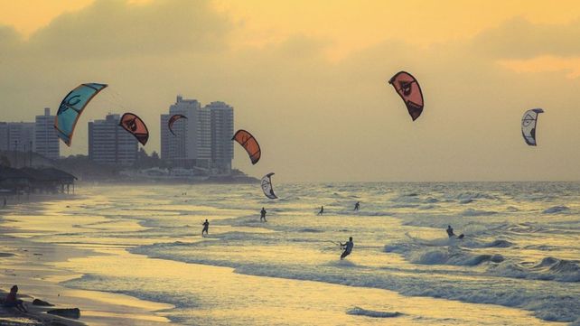 Una playa llena de personas haciendo kitesurf