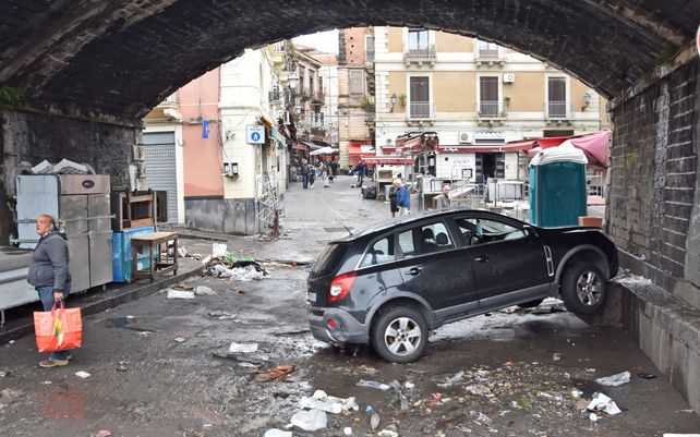 Un automóvil atascado debajo de un puente después de que las fuertes lluvias inundaron las calles de la ciudad siciliana de Catania