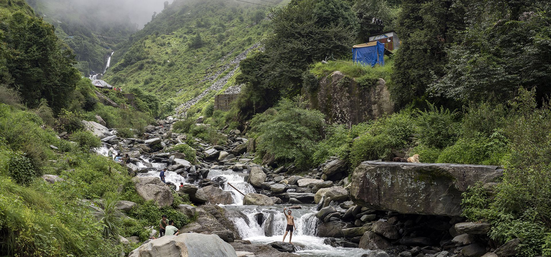 Un turista se toma una selfie mientras se baña en un arroyo de montaña en Dharmsala, India, el martes 2 de agosto de 2022.