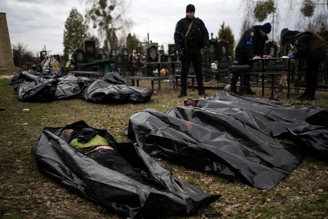 Un policía observa los cuerpos de civiles muertos en la ciudad de Bucha antes de que los cadáveres sean transportados a la morgue de Kiev.